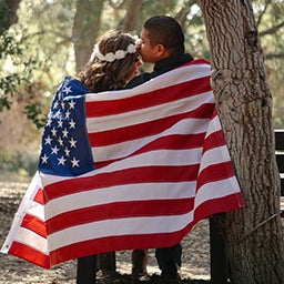 Couple snuggling under the American Flag as a symbol of military spouses